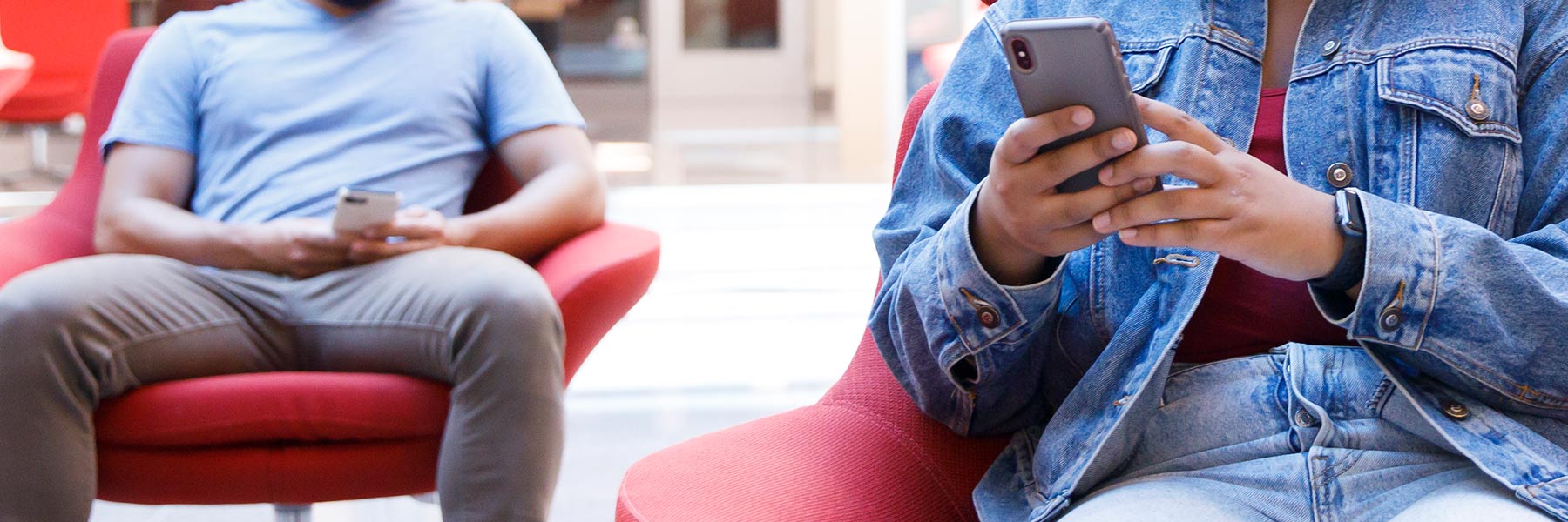 Two seated students using cellphones.