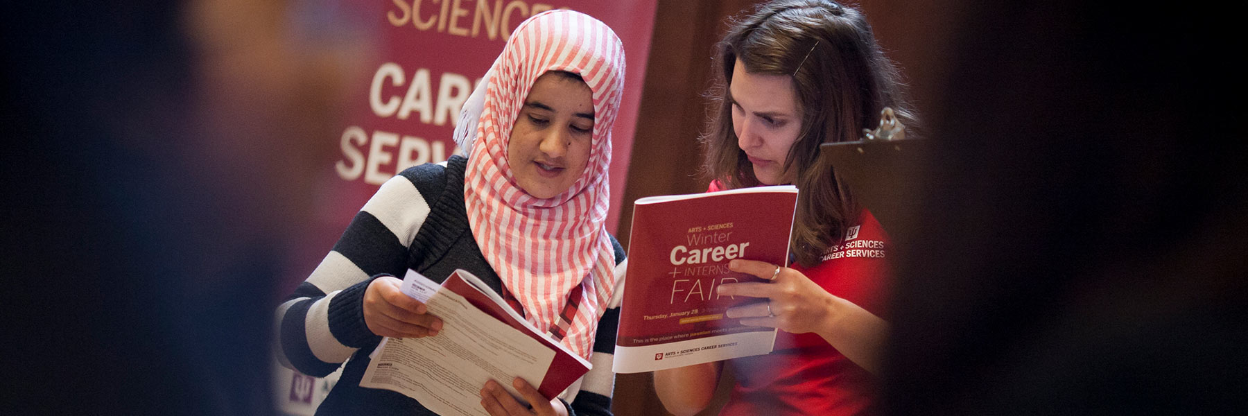 A student speaks to a career services representative at a job fair event.