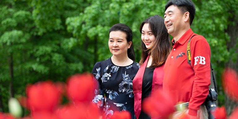 Two parents flank a graduate in commencement garb.